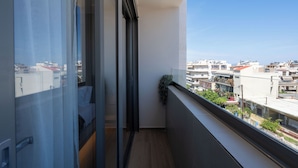 A balcony with a view of the cityscape, a sliding glass door, and a small plant on the railing. - Selected Suites  (Chania)