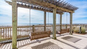 A wooden pergola with swings overlooking a beach. - 17th Floor Gulf Front Condo with Sunset Views from the Large Balcony (Gulf Shores)