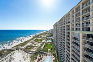 Un hôtel de grande hauteur doté de nombreux balcons offrant une vue sur une plage et l’océan.