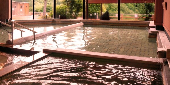 A hot spring bath with a wooden deck and a view of greenery outside. - Zuisenkyo (Ichinoseki)