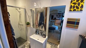Une salle de bain moderne équipée d’une douche, d’un lavabo et de serviettes suspendues.
