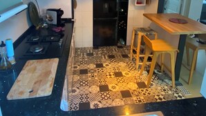 Une cuisine avec un réfrigérateur noir, une table à manger en bois et un sol à motifs.