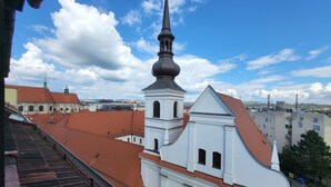 Una iglesia con un campanario alto y un techo de tejas rojas, vista desde un balcón.