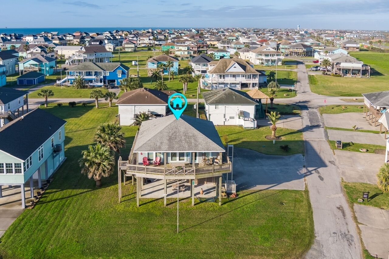 Un barrio residencial con una casa destacada que tiene un balcón y vista al océano.