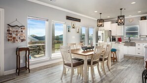 A spacious kitchen with white cabinets, a wooden dining table, and a view of the outdoors. - Big Chill 2 Bedroom Home (Port Bolivar)