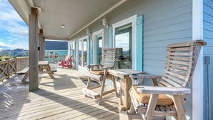 A wooden deck with outdoor seating and large windows. - Big Chill 2 Bedroom Home (Port Bolivar)