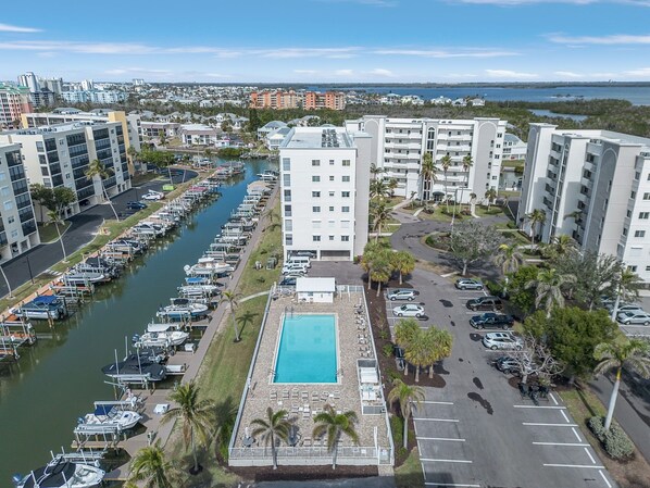 A marina with boats docked, a swimming pool, and adjacent parking. - Casa Marina 432 Newly Remodeled, Water View 2 Bedroom Condo (Fort Myers Beach)