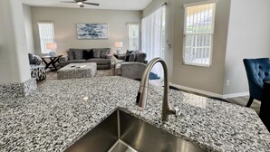 A kitchen with granite countertops, stainless steel sink, and a ceiling fan. - Tranquilo Villa A Shine Villas Property In Tuscan Hills 5 Bedroom Villa (Davenport)