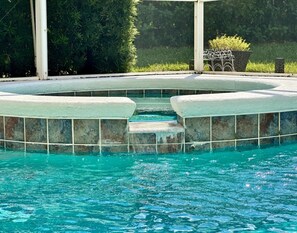 Ein Schwimmbecken mit Steinbord und Stufen zum Wasser.
