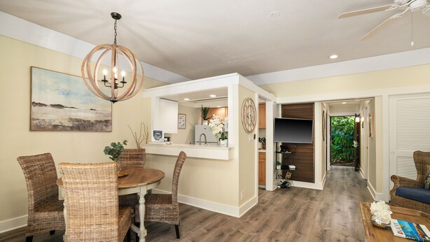 A dining area with wicker chairs, a wooden table, and a chandelier.