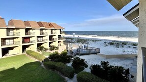 Ein Strandhotel mit mehreren Balkonen, einem Sandstrand und freiem Blick auf das Meer.
