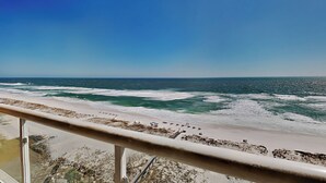 A beach view from a balcony with a railing, ocean waves, and a clear sky. - Emerald Isle | Corner Condo w. Pool/Hot Tub, Private Beach + More (Pensacola Beach)