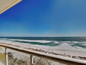 A beach view from a balcony with a railing, ocean waves, and a clear sky. - Emerald Isle | Corner Condo w. Pool/Hot Tub, Private Beach + More (Pensacola Beach)