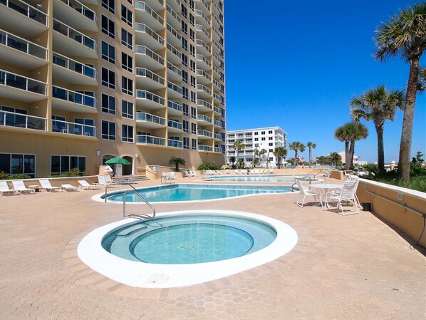 A hotel with a pool area, including a hot tub and lounge chairs. - Emerald Isle | Corner Condo w. Pool/Hot Tub, Private Beach + More (Pensacola Beach)