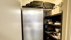 A compact kitchen with a stainless steel refrigerator, a small sink, and a shelf with kitchen items. - Apartment in Middelkerke Near the Beach (Middelkerke)
