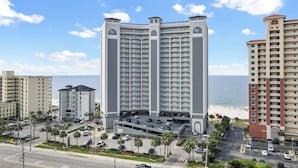 Un hôtel de grande hauteur doté de nombreux balcons, d’un parking souterrain et offrant une vue sur la plage.