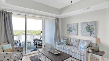 A spacious living area with a sofa, a coffee table, and a sliding glass door leading to an outdoor patio.