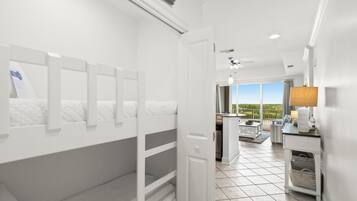 A hotel room with bunk beds, a balcony with a view, a kitchen area, and a large window.