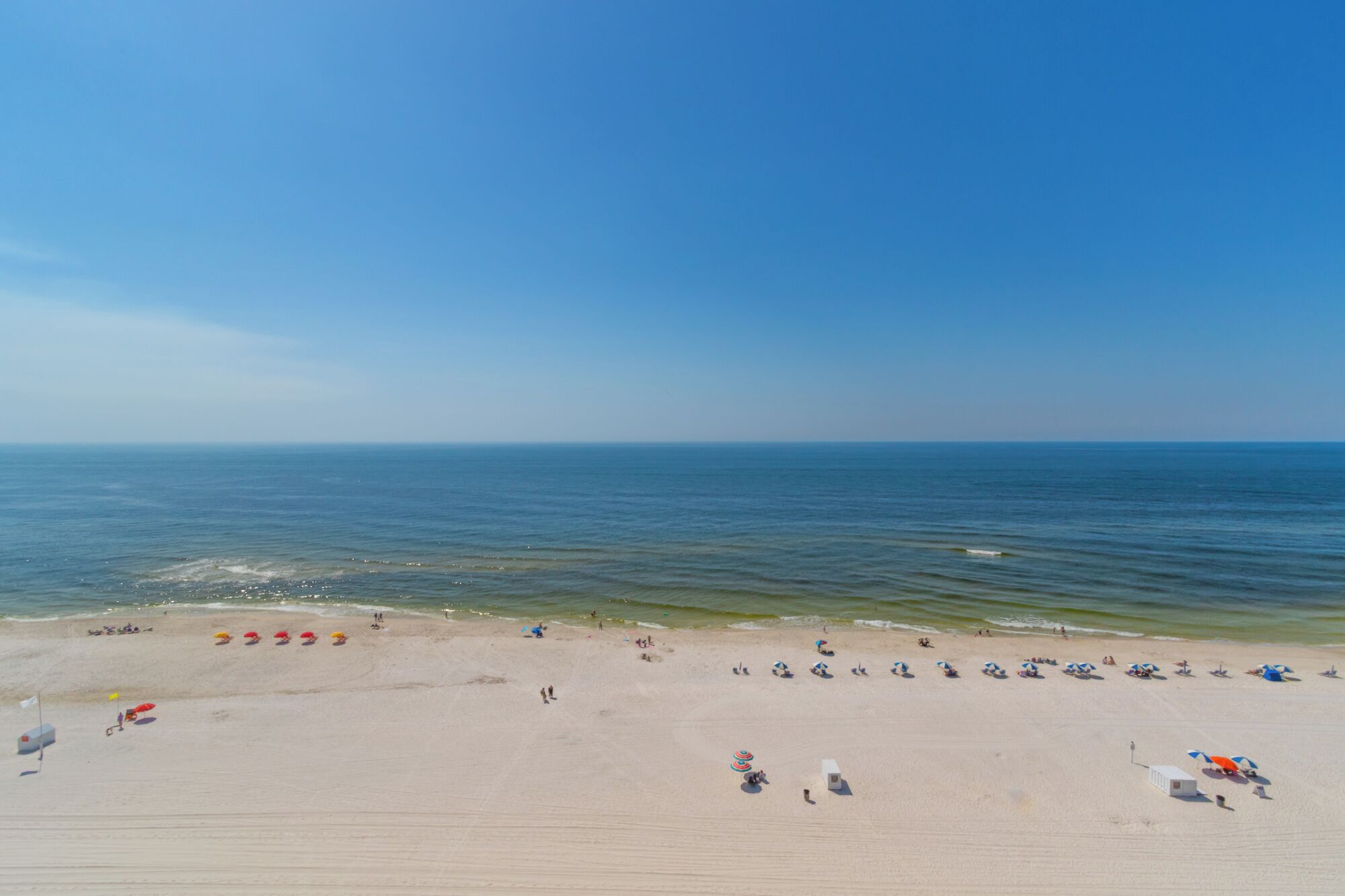 Een breed zandstrand met een helder uitzicht op de oceaan.