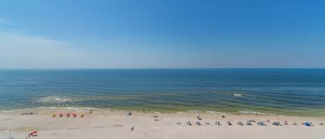 Een breed zandstrand met een helder uitzicht op de oceaan.