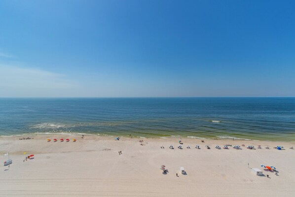 Uma extensa praia de areia com vista clara para o oceano.