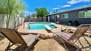 Un jardin avec une piscine, des chaises longues et une maison.