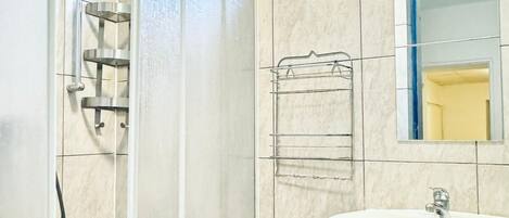 Un baño con ducha de vidrio, lavamanos y espejo.