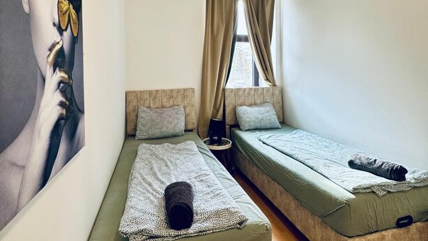 Une chambre avec deux lits, un grand tableau au mur et une fenêtre avec des rideaux.
