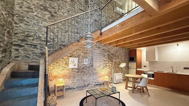 A modern interior with a stone wall, a staircase, a dining area, and a kitchen. - Agi Porthos 800 Apartamento for rent in Roses Girona. (Roses)
