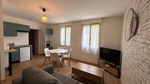 Un espacio habitable compacto con kitchenette, comedor y zona de estar con televisor de pantalla plana.