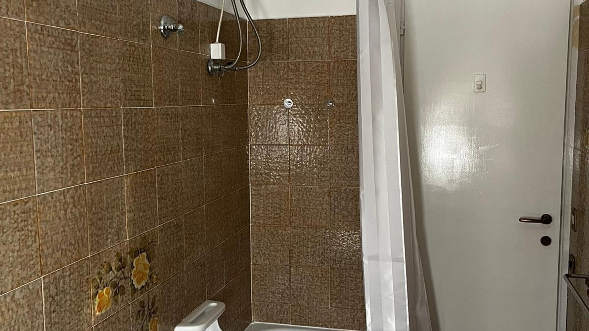 Kylpyhuone, jossa on laatoitetut seinät, suihku ja wc.