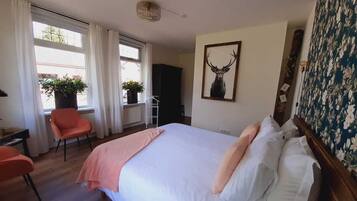 Relax in comfort with a large bed, a cozy chair, and a beautiful view.