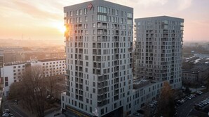 Two high-rise buildings with a modern architectural design, featuring a prominent sign at the top of the left building. - Tower II by Kairos Apartments (Katowice)