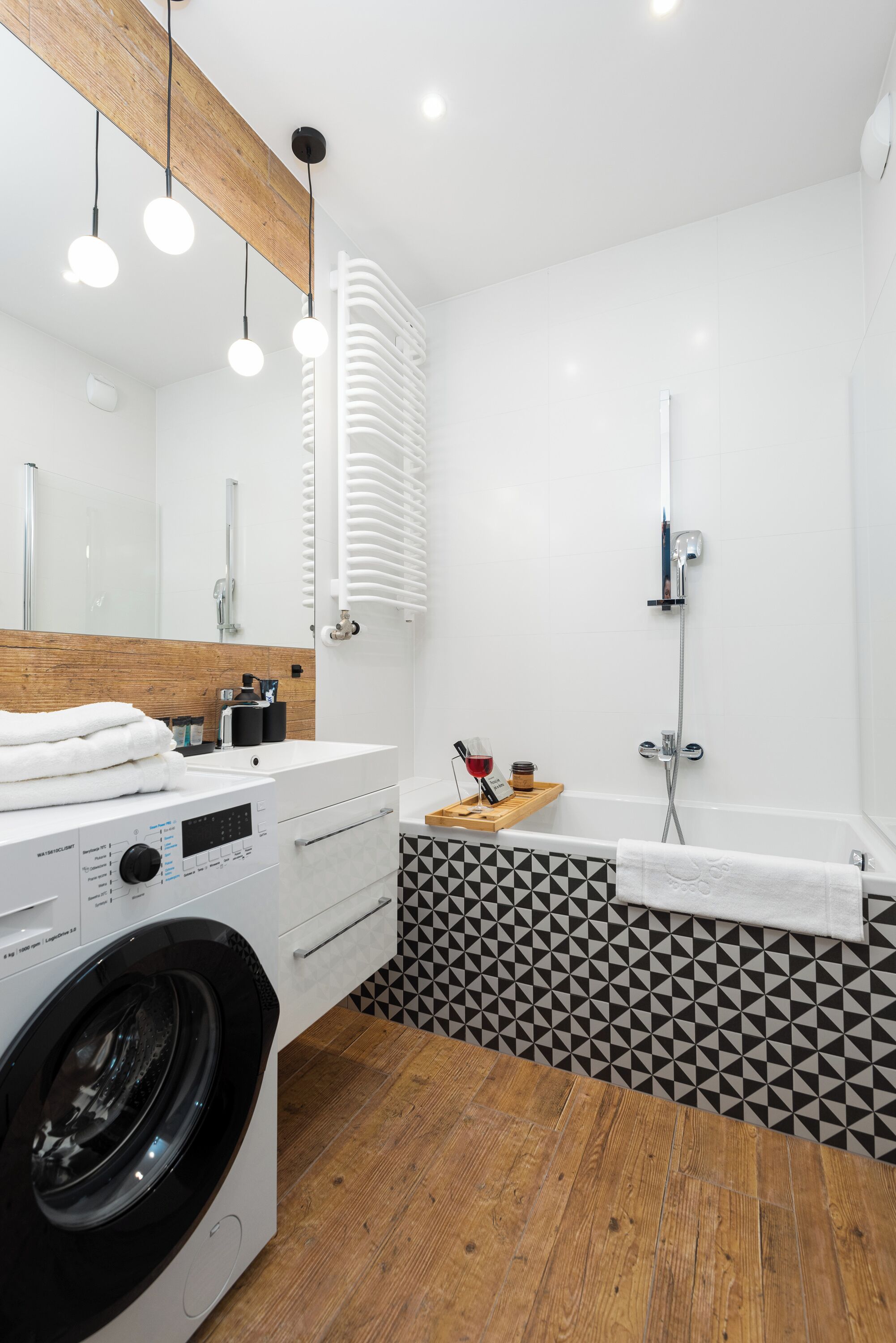 A modern bathroom with a washing machine, a sink, a mirror, and a shower.