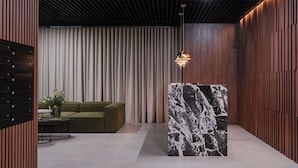 A modern interior with a sofa, a marble accent wall, and a pendant light. - Tower II by Kairos Apartments (Katowice)