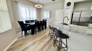 Eine moderne Küche mit einem Edelstahlkühlschrank, einer Granit Arbeitsplatte und einem Essbereich mit Tisch und Stühlen.