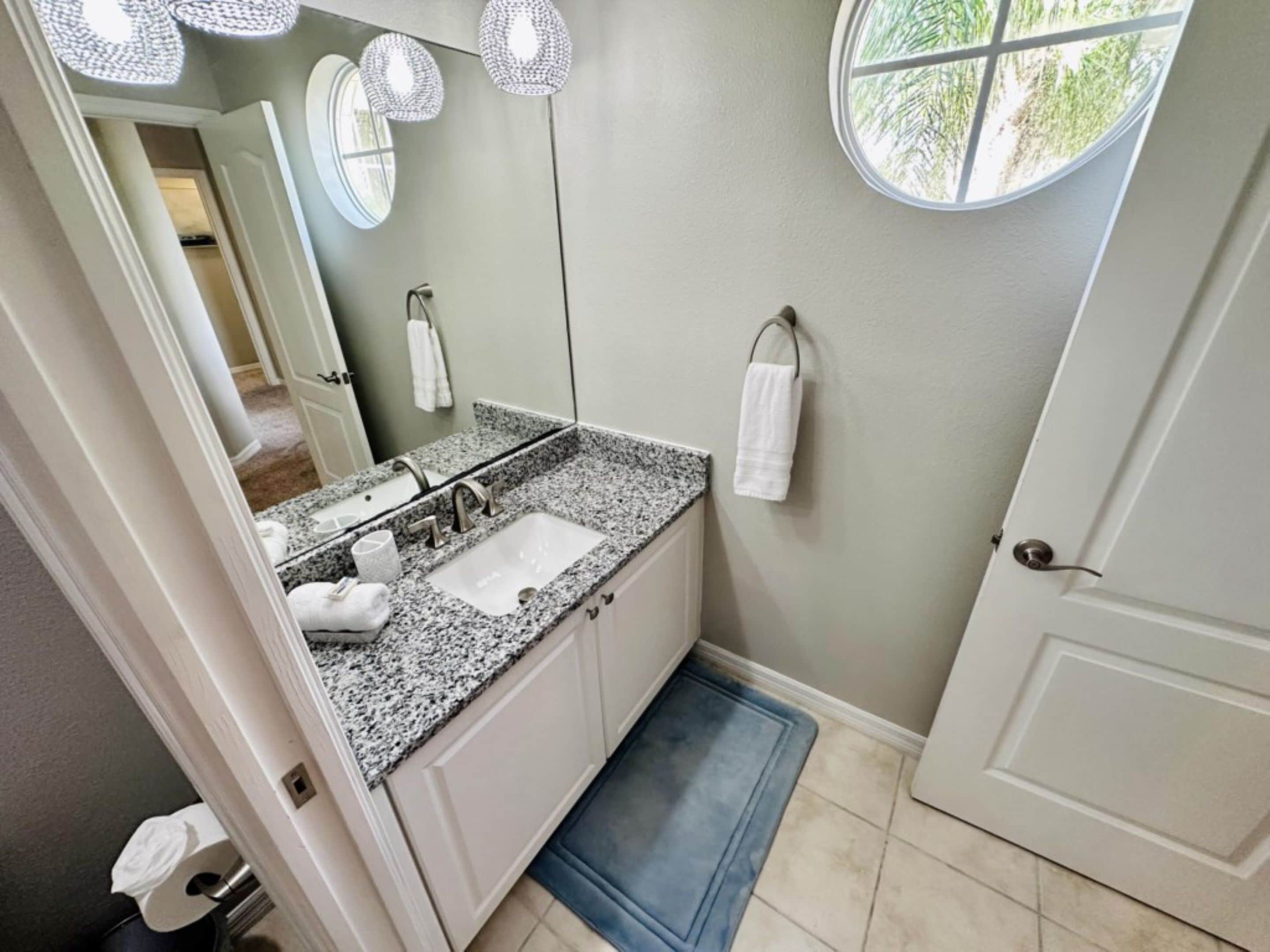 A bathroom with a granite countertop, a sink, a mirror, and a towel rack.