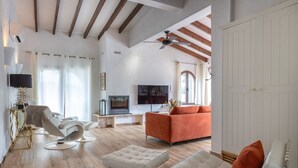 Ein geräumiges Wohnzimmer mit einem modernen Sofa, einem Liegesessel, einem Fernseher und einem Kamin.