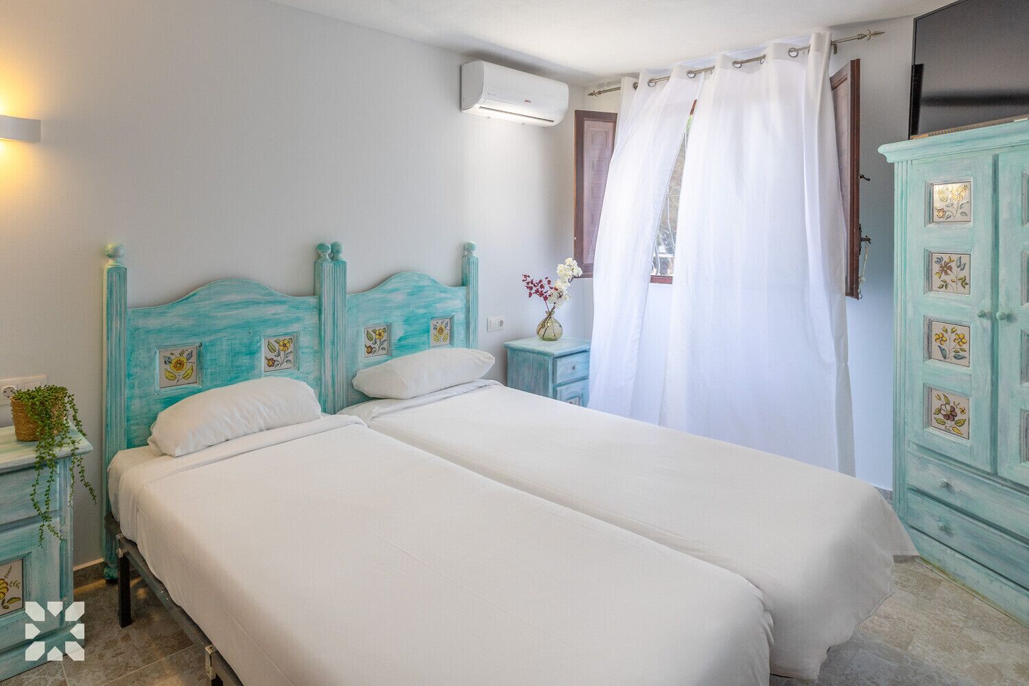 A bedroom with two beds, a nightstand, a dresser, and a window with curtains.