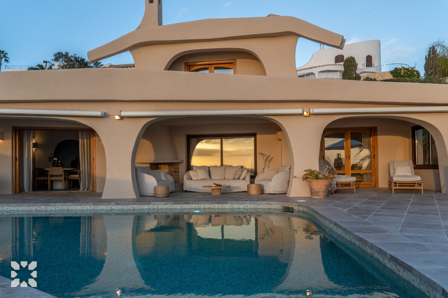 A modern house with a swimming pool, outdoor seating, and a patio area.