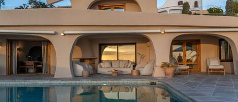 A modern house with a swimming pool, outdoor seating, and a patio area.