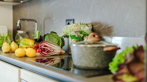 Eine Küchenarbeitsplatte mit frischem Obst und Gemüse, einer Spüle und einem Kochtopf.