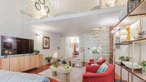 Ein modernes Wohnzimmer mit Flachbildfernseher, roten und blauen Sofas, einem Couchtisch und einem dekorativen Regal.