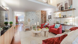 Ein geräumiger Wohnbereich mit einem roten Sofa, zwei runden Couchtischen, einer Treppe und einem Bücherregal mit Dekoration.