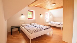Une chambre avec deux lits, un plancher en bois et un plafond en pente.