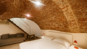 A bedroom with a brick ceiling, a staircase, a bed, a nightstand, and a lamp. - dHomes -Loft suite in Duomo (Milan)