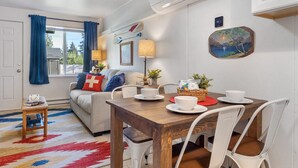 Ein gemütliches Wohnzimmer mit einer Couch, einem Holzesstisch und einem Fenster mit Vorhängen.