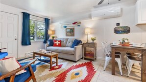 Ein Wohnzimmer mit einer Couch, einem Esstisch und einem Deckenventilator.
