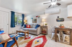 Un salon avec un canapé, une table à manger et un ventilateur de plafond.