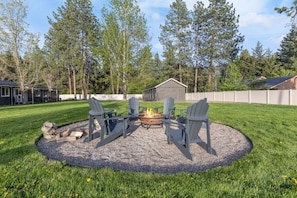 Un espace extérieur circulaire aménagé avec des chaises Adirondack et un foyer.